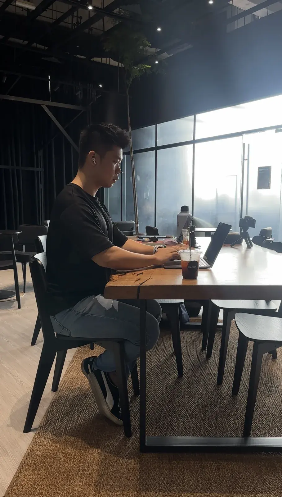Adrian Ching working at a laptop beside a café window